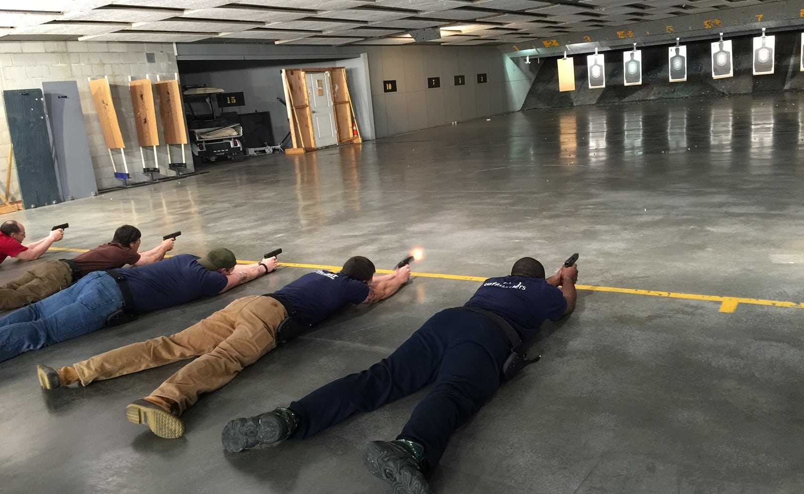 People practicing shooting at indoor firing range.